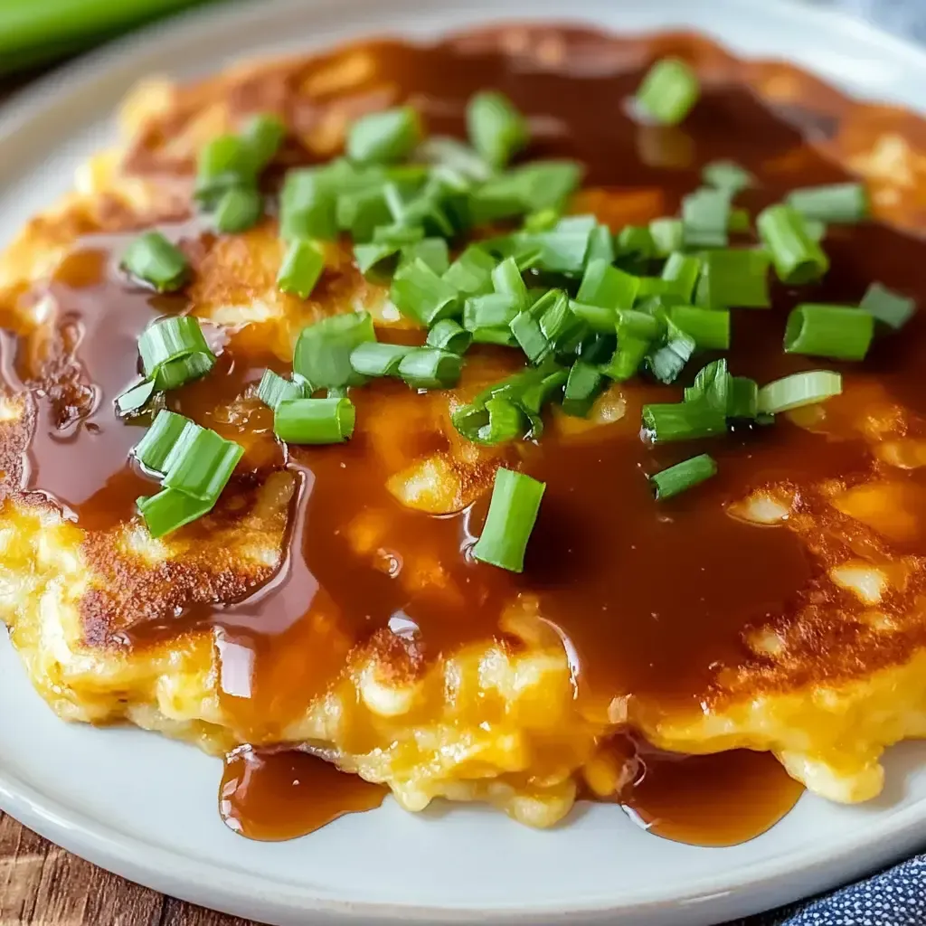 Eine Platte mit Pancakes, die mit Sauce und grünen Zwiebeln garniert sind.