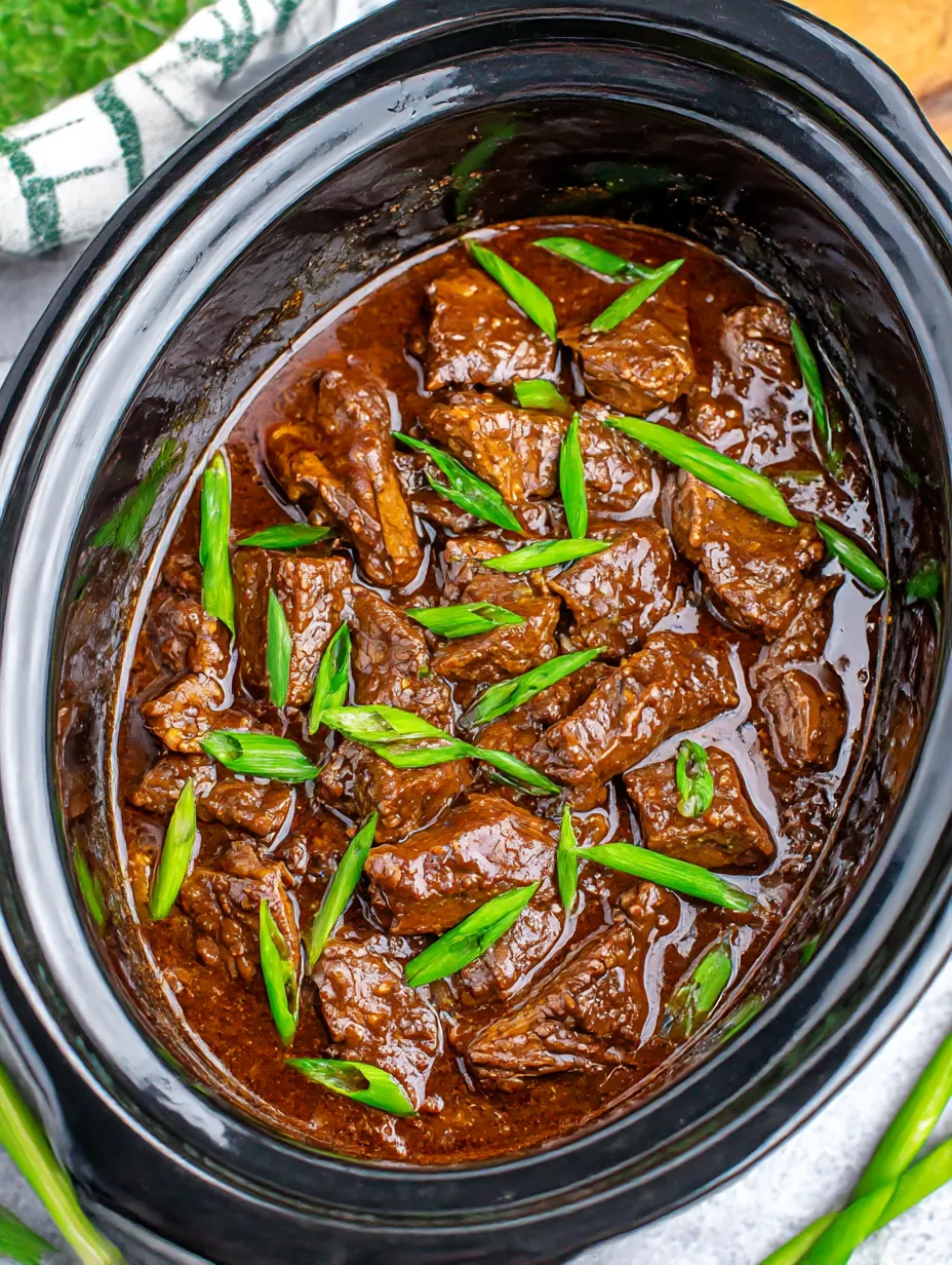 Ein Topf mit slow cooker Mongolian Beef, das in einem Topf mit einer braunen Sauce gart.